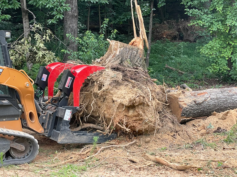 Maxilator farm debris grapple clearing a tree stump off the farm using bucket and claws